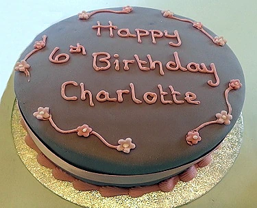 Birthday cake with pink icing and piped lettering